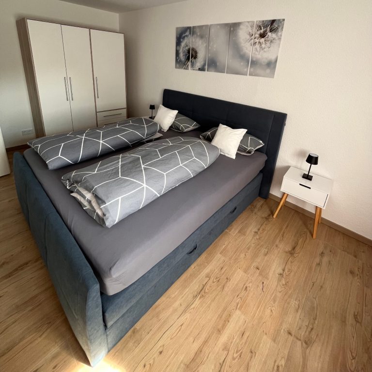 Casa Heckl Ferienwohnung Tutzing Traubing Starnberger See Gemütliches Schlafzimmer mit Doppelbett, Nachttisch und modernem Dekor.