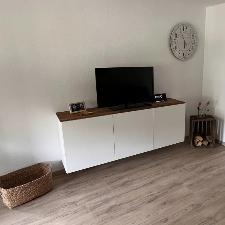 Modernes Wohnzimmer mit TV, weißem Schrank, einem Korb und Wanduhr. Modernes Wohnzimmer mit TV, weißem Schrank, einem Korb und Wanduhr.