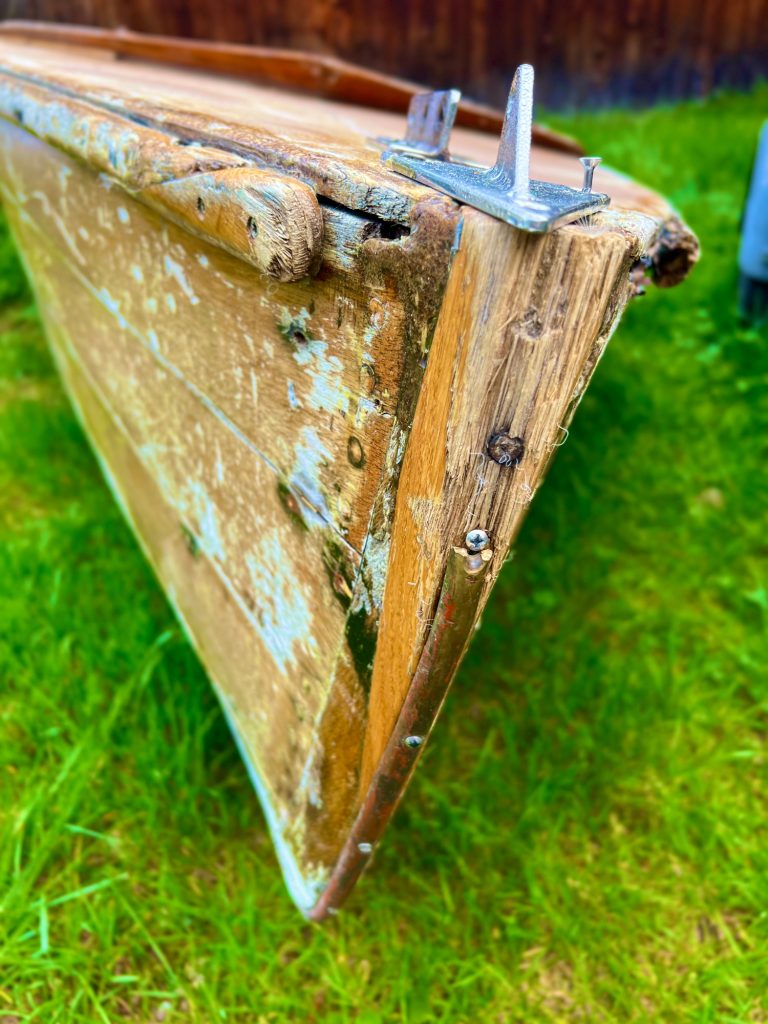 Tutzing Traubing Ferienwohnung Casa Heckl Gestartetes Holzboot mit beschädigtem Rumpf im Gras.