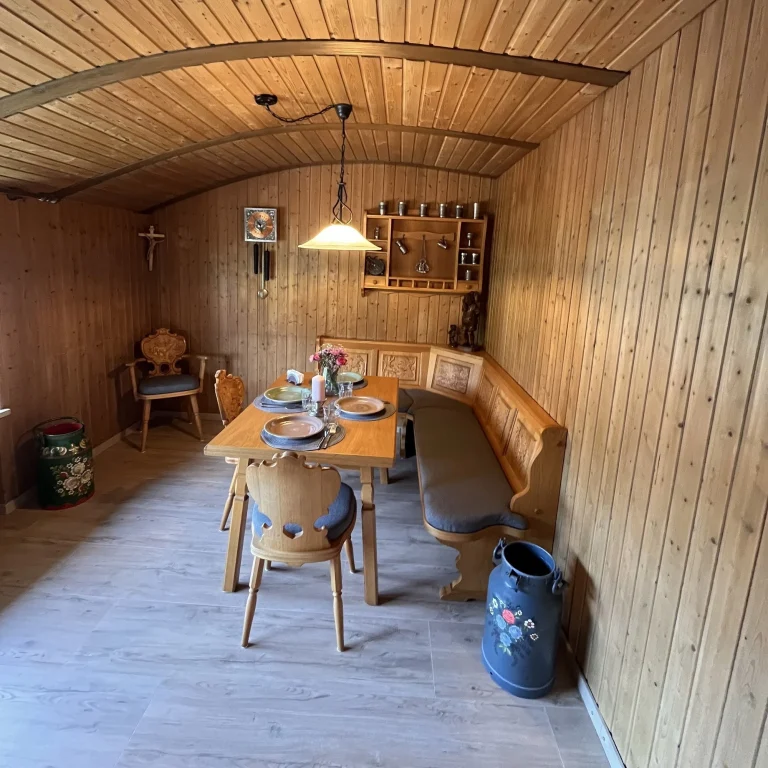 Uriges-bayrische-stube-als-essbereich Gemütlicher Holzraum mit Essbereich, Tisch, Bänken und Dekoration an der Wand.