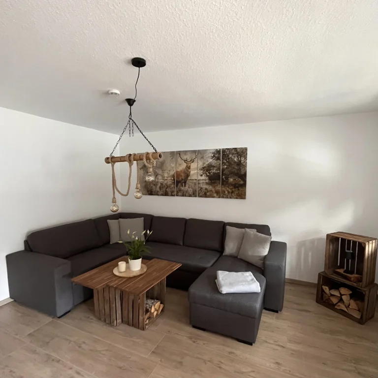 Modernes helles Wohnzimmer mit U-förmigem Sofa, Holztisch und einer dekorativen Wandkunst im Landhaus Stil. Modernes helles Wohnzimmer mit U-förmigem Sofa, Holztisch und einer dekorativen Wandkunst im Landhaus Stil.